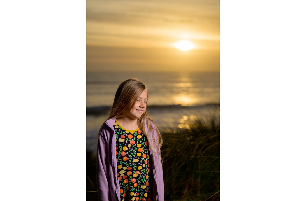 A girl smiling as she poses at sunset on the beach